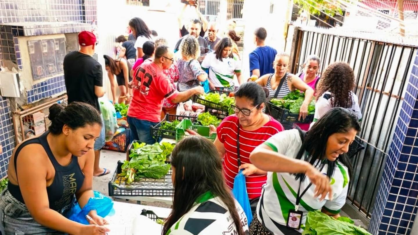 Moradores escolhem verduras, legumes e frutas durante uma distribuição de alimentos do Instituto AMEAS.