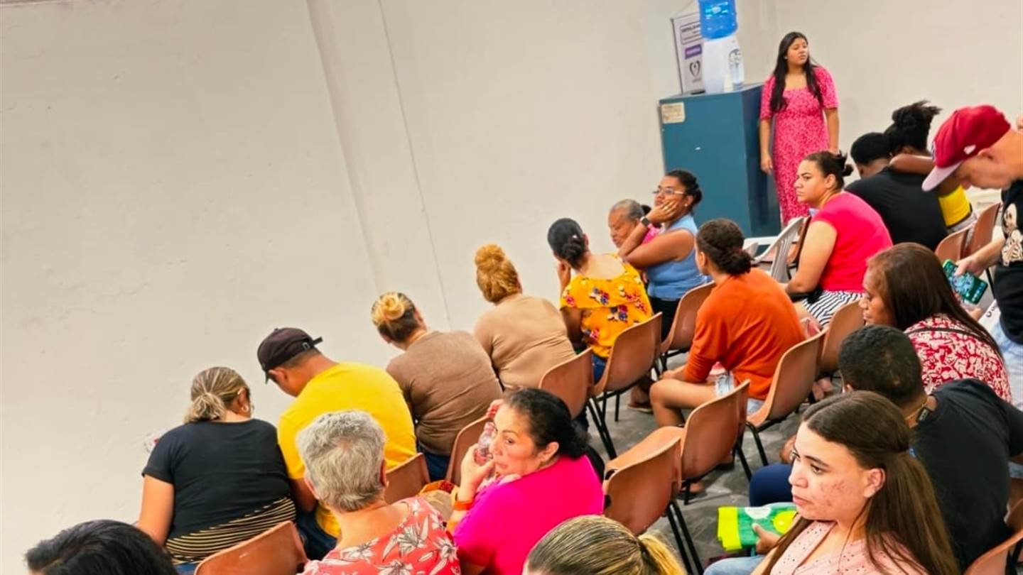 Roda de conversa na sede: uma facilitadora fala em pé para moradores sentados em cadeiras.