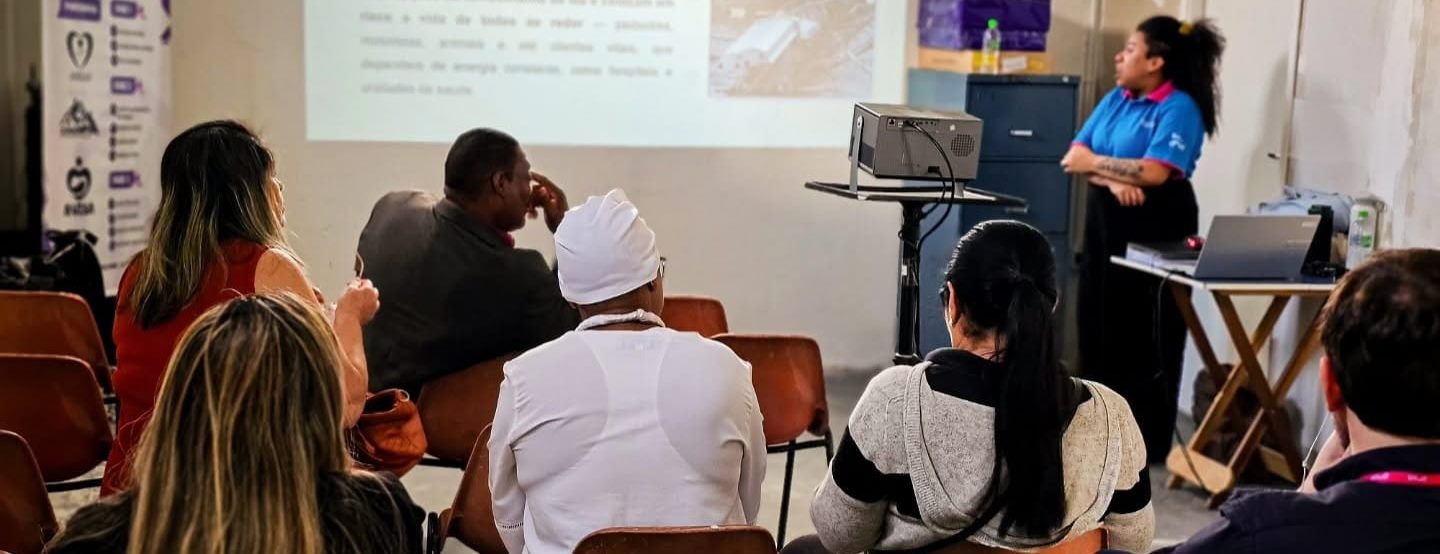 Turma acompanha uma aula de capacitação com projetor no salão da sede do Instituto AMEAS.
