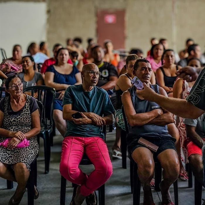 Coordenador conversa com moradores durante uma assembleia comunitária lotada.